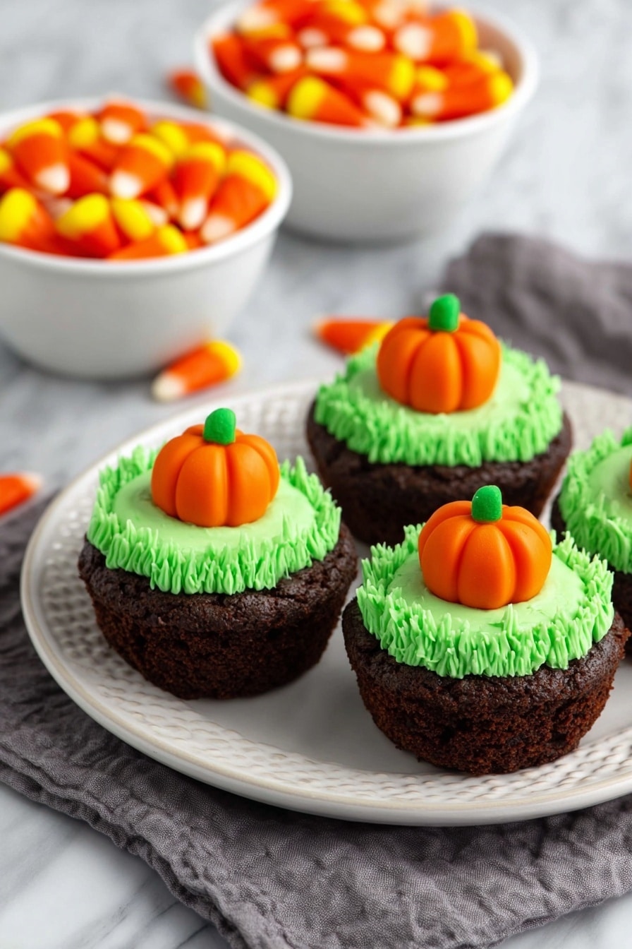 Pumpkin Patch Brownie Bites, fall dessert ideas, Halloween treats, festive brownie bites, pumpkin Halloween snacks - The image shows a close-up of a rich, dark brown brownie cupcake on a white plate with a white marbled background. The cupcake has one layer of dense, moist chocolate cake with a slightly rough texture. On top is a thick swirl of bright green frosting, piped in tight loops to form a textured ring around the center. In the center of the frosting sits a small, smooth orange pumpkin-shaped candy with green leaves on top, adding a pop of color and detail. Photo taken with an iphone --ar 2:3 --v 7