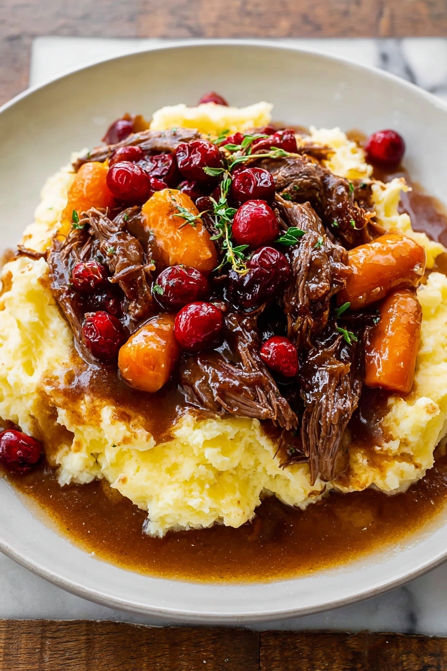 Cranberry Balsamic Roast Beef, roast beef with cranberries and balsamic, festive beef roast recipe, easy holiday roast beef, tender roast beef for dinner - A white plate holds a dish with three main layers: the base is a thick, creamy mashed potato layer, pale yellow and textured with soft peaks; on top of that sits a rich brown gravy mixed with tender, shredded dark brown beef pieces; the top layer features bright orange carrot slices and glossy red cranberries scattered throughout, with small green herb sprigs for garnish. The gravy looks shiny and slightly thick, pooling a little on the plate around the mashed potatoes. The whole plate is on a white marbled surface. photo taken with an iphone --ar 2:3 --v 7