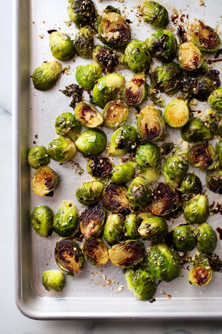 Best Roasted Brussels Sprouts, roasted Brussels sprouts, crispy Brussels sprouts, healthy Brussels sprouts side dish, easy Brussels sprouts recipe - The image shows a single layer of roasted Brussels sprouts spread out on a white baking sheet. The Brussels sprouts are halved or quartered, with some pieces whole, and they have a mix of bright green and dark brown charred edges. Small bits of garlic and coarse salt are scattered on top, adding texture. There are also spots of dark balsamic glaze drizzled over some of the sprouts. The white baking sheet sits on a white marbled surface, with light reflecting softly on it. photo taken with an iphone --ar 2:3 --v 7