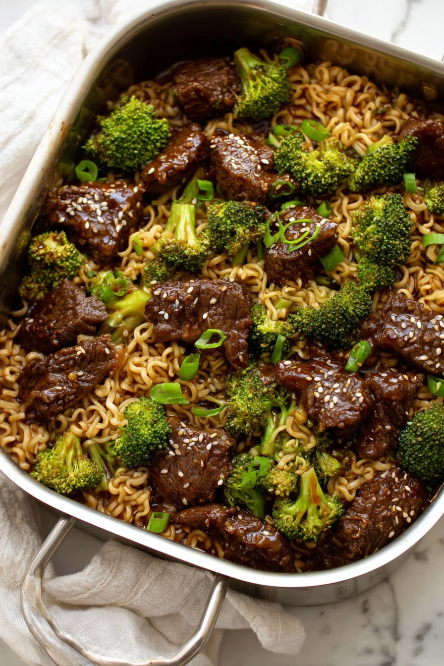 Beef and Broccoli Ramen Stir Fry, Beef and Broccoli Stir Fry, Ramen Noodle Stir Fry Recipes, Easy Beef Stir Fry, Quick Ramen Dinner - A metal pan filled with a mixture of three main layers: the first layer is curly light brown noodles that look soft and slippery, the second layer is bright green broccoli florets spread evenly, and the third layer is dark brown pieces of cooked beef scattered throughout. The beef pieces have a shiny glaze on them and some white sesame seeds sprinkled on top. Small pieces of chopped green onion add small bright green spots among the noodles and beef, all resting on a white marbled surface with a white cloth in the background. photo taken with an iphone --ar 2:3 --v 7