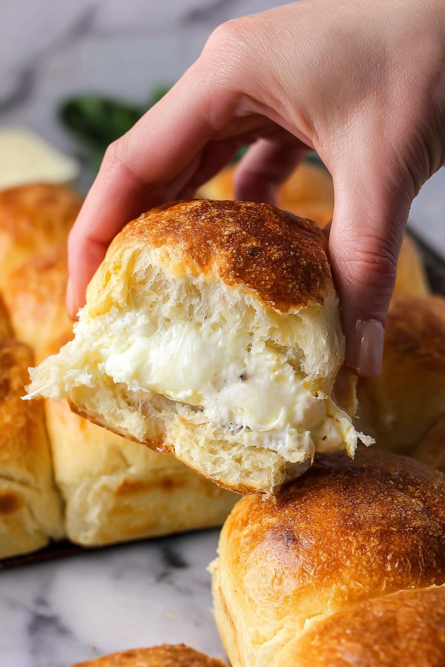 Cheesy Garlic Butter Pull Apart Rolls, cheesy garlic bread ideas, soft bread rolls with cheese and garlic, homemade pull apart bread recipes, easy cheesy bread rolls - A woman's hand is pulling apart a soft bread roll that is golden brown on top with a slightly crispy crust. Inside, there is one thick, melted white cheese layer with a creamy texture visible in the center. The background shows more bread rolls that are golden on top, all placed on a white marbled surface. The photo taken with an iphone --ar 2:3 --v 7