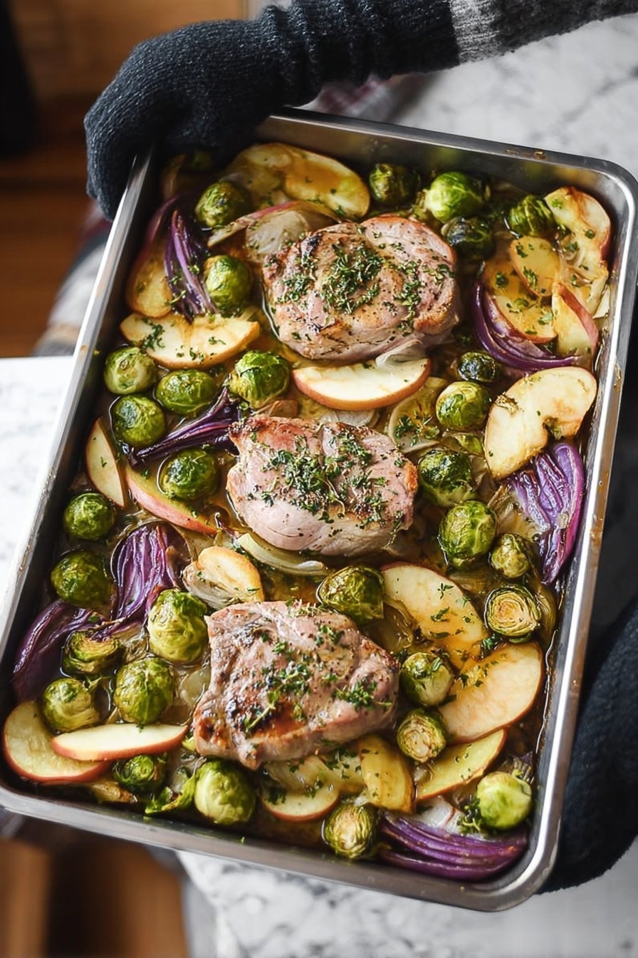Sheet Pan Pork Chop Supper, quick pork chop dinner, easy weeknight pork recipes, one-pan pork and veggies, juicy bone-in pork chops - A metal baking tray with four large light pink pork pieces in the center, sprinkled with green herbs, surrounded by bright green halved Brussels sprouts and wedges of purple-red onion and golden brown apple slices, all on a white marbled surface. Steam rises from the tray, held by a woman’s hand wearing a black glove on the left side. The vegetables and pork look roasted with some browned edges. photo taken with an iphone --ar 2:3 --v 7