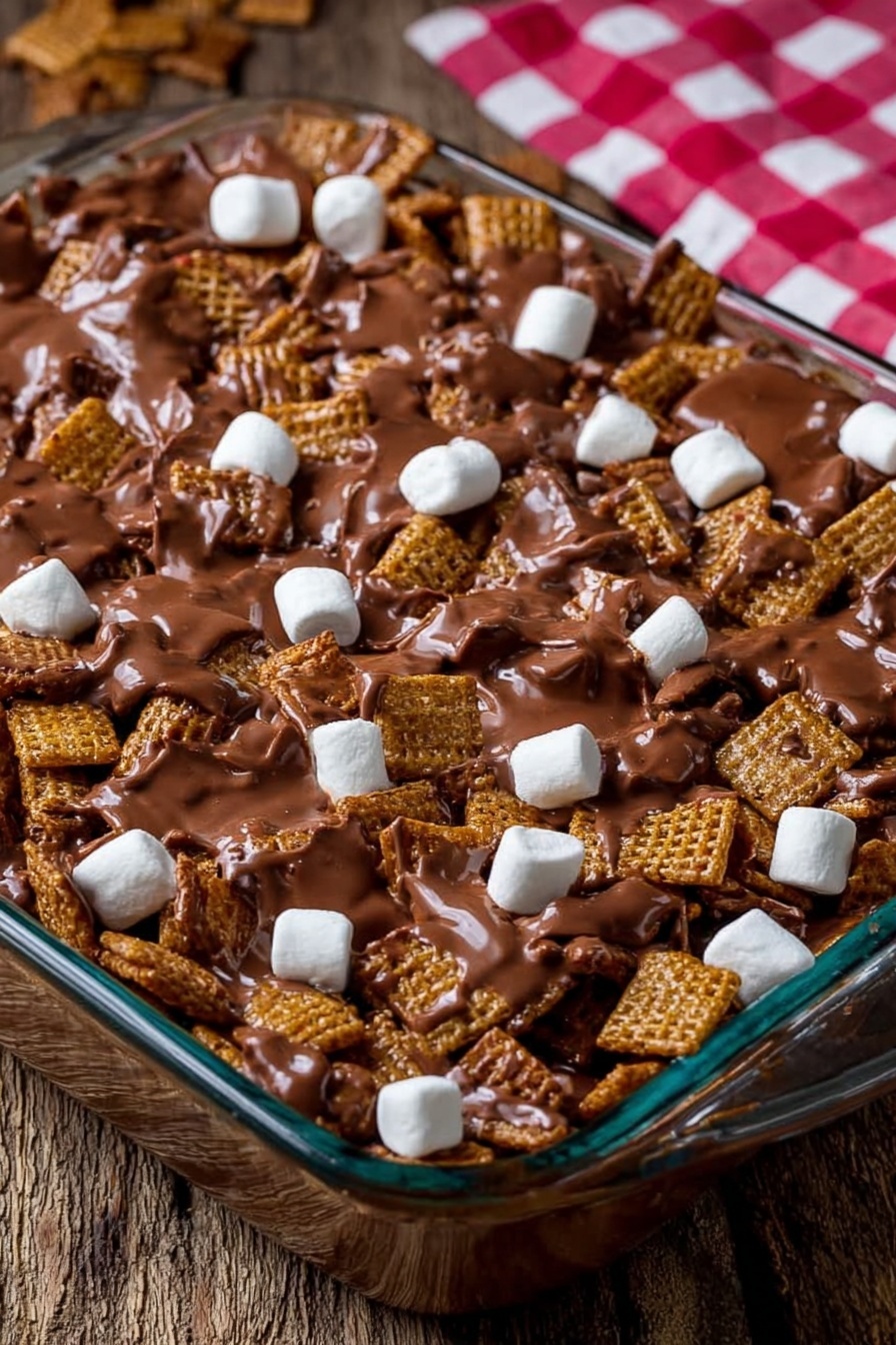 Golden Grahams s'mores bars, s'mores dessert bars, campfire s'mores treats, easy s'mores bars, no-bake cereal bars - The image shows a clear glass baking dish filled with a mix of square cereal pieces covered in melted milk chocolate, creating a shiny, smooth brown layer that coats the cereal unevenly. Scattered throughout the top are small, white marshmallows that stand out against the chocolate and cereal mix. The dish is placed on a rough wooden surface with a blurred red and white checkered cloth in the background. Photo taken with an iphone --ar 2:3 --v 7