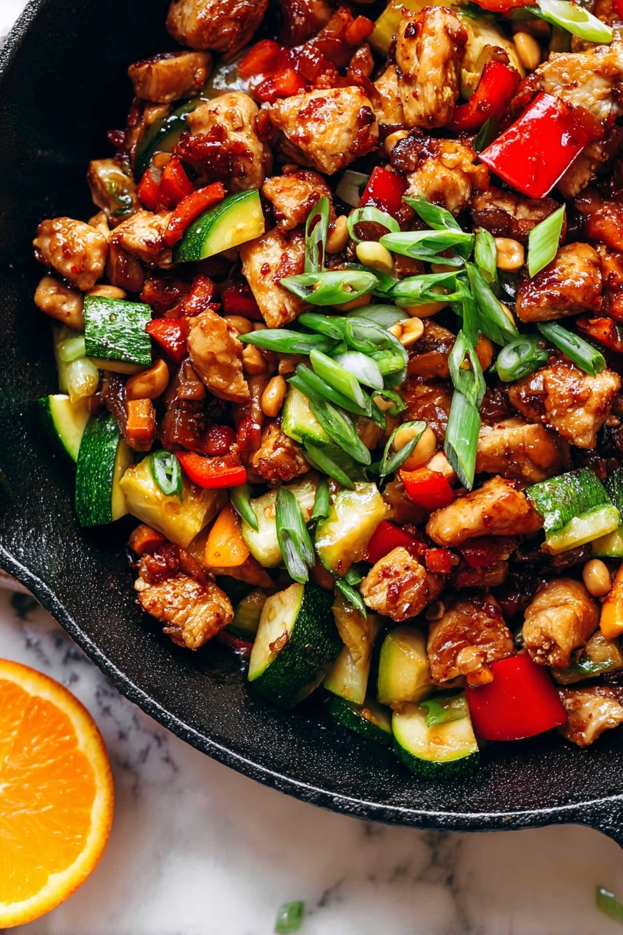 Kung Pao Chicken, Chinese stir-fry, spicy chicken dishes, homemade Kung Pao, Asian chicken recipes - The image shows a close-up of a black cast iron pan filled with a colorful stir-fry dish that has three main layers. The first layer has browned chicken cubes with a shiny, caramelized texture scattered throughout the pan. The second layer has chopped vegetables, including bright red bell peppers and chunks of green zucchini with a cooked but firm look. The third layer is made up of small, light brown peanuts and thin slices of green onions sprinkled on top, adding a fresh touch. The pan sits on a white marbled surface, and there is a slice of bright orange on the edge of the pan. The light in the photo makes the food look vibrant and appetizing photo taken with an iphone --ar 2:3 --v 7