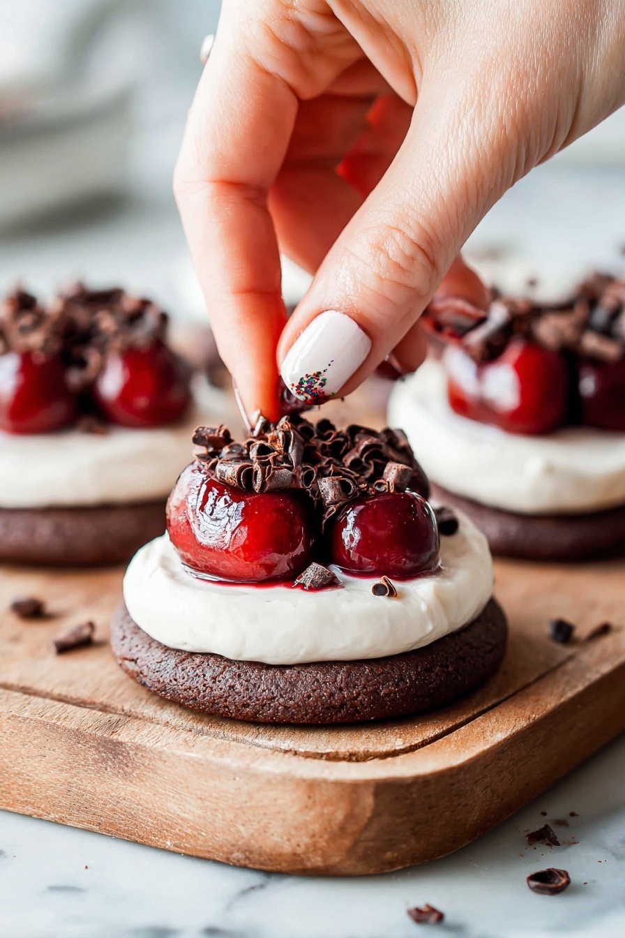 Chocolate Cherry Cheesecake Cookies, cherry chocolate cookie recipe, no-bake cheesecake cookies, easy fruit dessert cookies, chocolate cherry dessert - The image shows a dessert made of three layers on a wooden board: the bottom layer is a round, dark brown chocolate cookie with a soft texture; the middle layer is a thick, smooth white cream spread evenly over the cookie; the top layer is bright red cherries sitting in a shiny glaze, garnished with small dark brown chocolate curls scattered on top and around the dessert. A woman's hand with painted nails is placing one of the chocolate curls on the cherries. The background is a white marbled texture. photo taken with an iphone --ar 2:3 --v 7