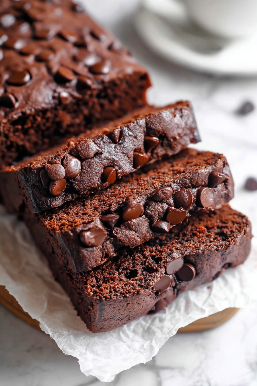 Chocolate Brownie Bread, fudgy chocolate bread, easy chocolate dessert, moist chocolate loaf, chocolate baking ideas - A stack of five thick, square chocolate brownies arranged diagonally on crinkled white parchment paper over a white marbled surface. Each brownie has a slightly cracked, shiny top layer with scattered dark chocolate chips embedded across the surface. The brownies show a dense, moist, and rich dark brown interior. Photo taken with an iphone --ar 2:3 --v 7