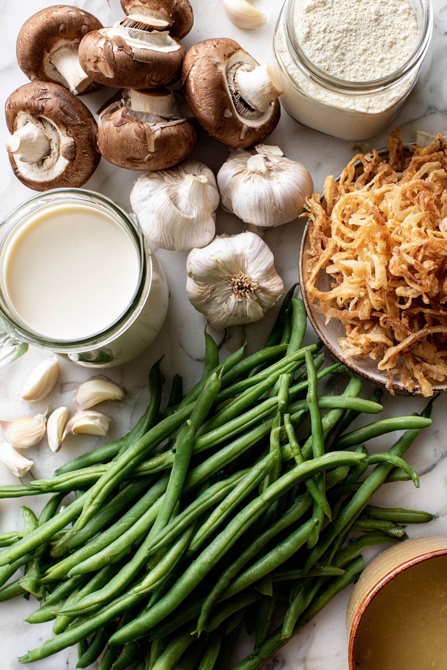 Vegan Green Bean Casserole, plant-based green bean casserole, dairy-free green bean side dish, vegan holiday side recipe, crispy fried onion green beans - Flat lay of fresh green beans with vibrant deep green hues, a cluster of earthy brown sliced mushrooms showing their soft texture, several plump garlic cloves with smooth off-white skin, a small mound of golden crispy french fried onions with a crunchy look, a glass jug of creamy white coconut-almond creamer, a clear container of pale beige raw flour, and a small bowl of rich golden vegetable broth, all naturally arranged with some beans and garlic cloves gently overlapping, placed on white marbled surface, photo taken with an iphone --ar 2:3 --v 7