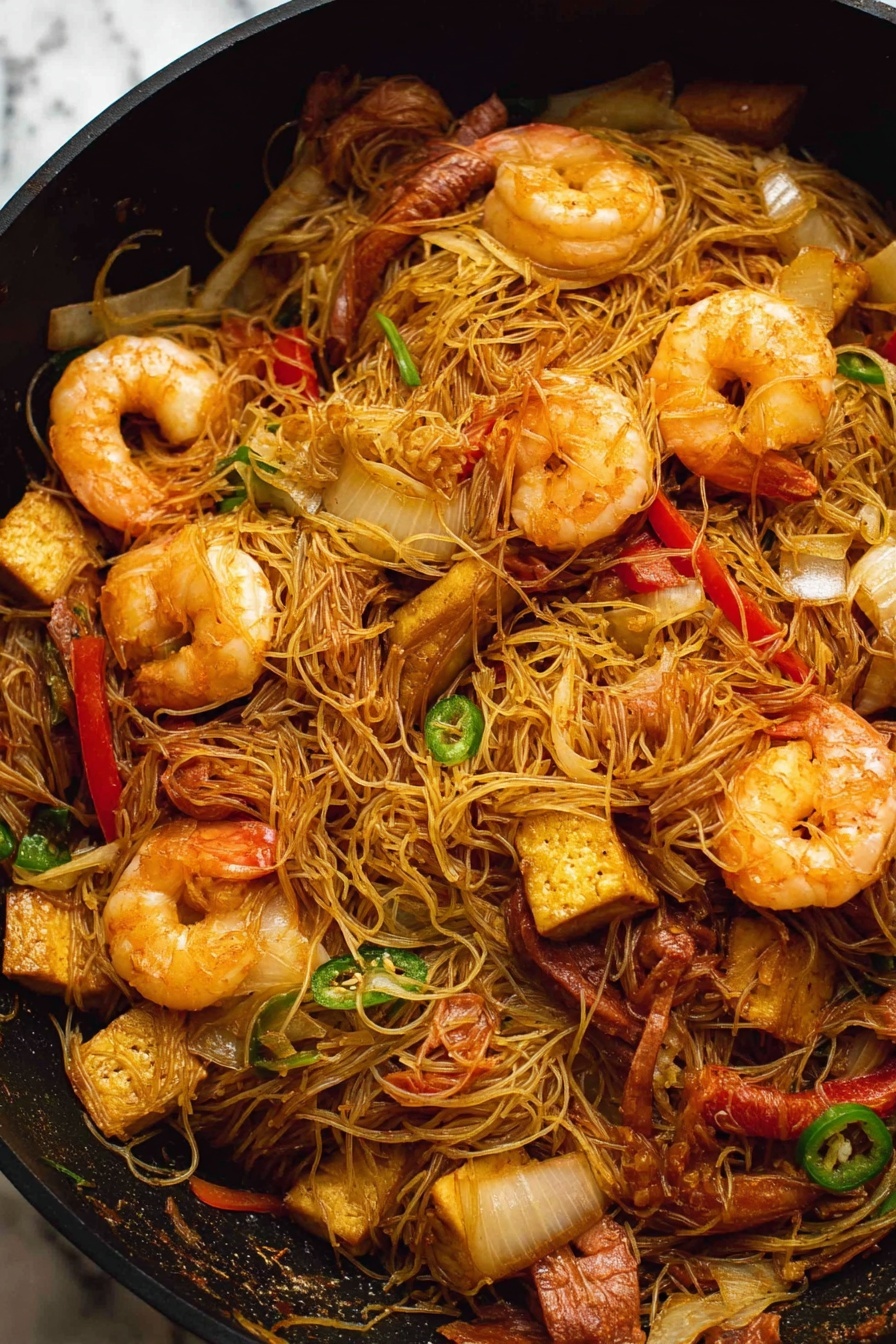 Singapore Noodles with Shrimp and Curry, quick Asian stir-fry, shrimp curry noodle recipe, easy Singapore noodle dish, flavorful rice vermicelli stir-fry - A black pan filled with stir-fried thin noodles mixed with large cooked shrimp that are a light orange color with a slightly shiny texture. There are pieces of sliced red bell pepper and green chili scattered throughout the noodles, along with chunks of browned tofu that have a slightly crispy outside. Thin slices of cooked brown meat and translucent, soft-looking onion slices are also mixed in. The noodles are tangled and lightly coated in a soy-colored sauce. The background is a white marbled texture. photo taken with an iphone --ar 2:3 --v 7