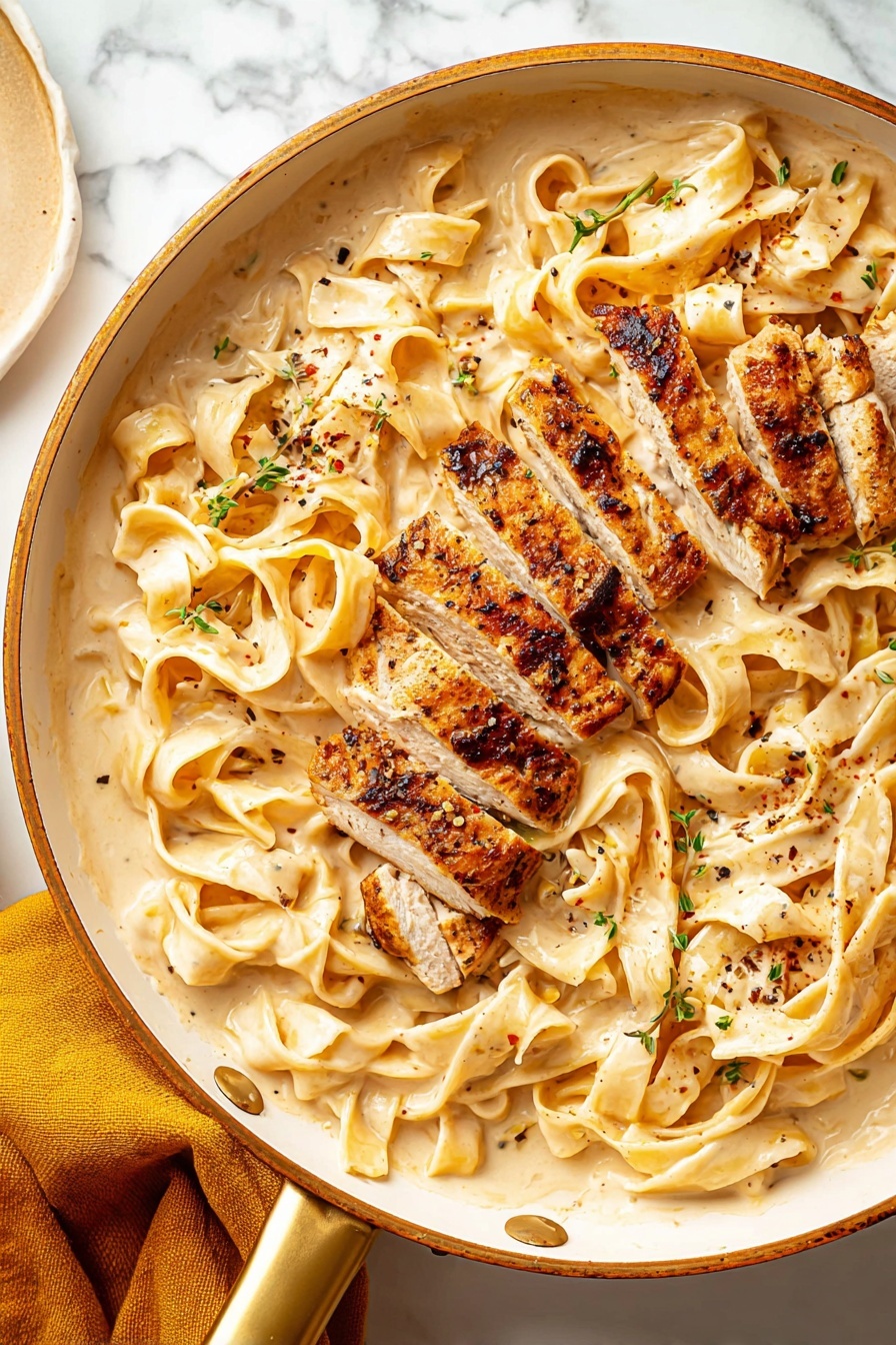 Creamy Fettuccine Alfredo with Chicken, Italian pasta with chicken, easy creamy chicken pasta, homemade Alfredo sauce, quick weeknight dinner - This image shows a white pan with a gold handle filled with wide flat noodles in a creamy light beige sauce, spread evenly across the pan as the bottom layer. On top, there are several thick pieces of grilled chicken, cut into strips with a browned, slightly charred crust and tender, light-colored inside. Small green herb bits and black pepper flakes are sprinkled over the noodles and chicken, adding texture and color contrast. The pan is placed on a white marbled surface, with a mustard yellow cloth partially visible on the lower left side. Photo taken with an iphone --ar 2:3 --v 7