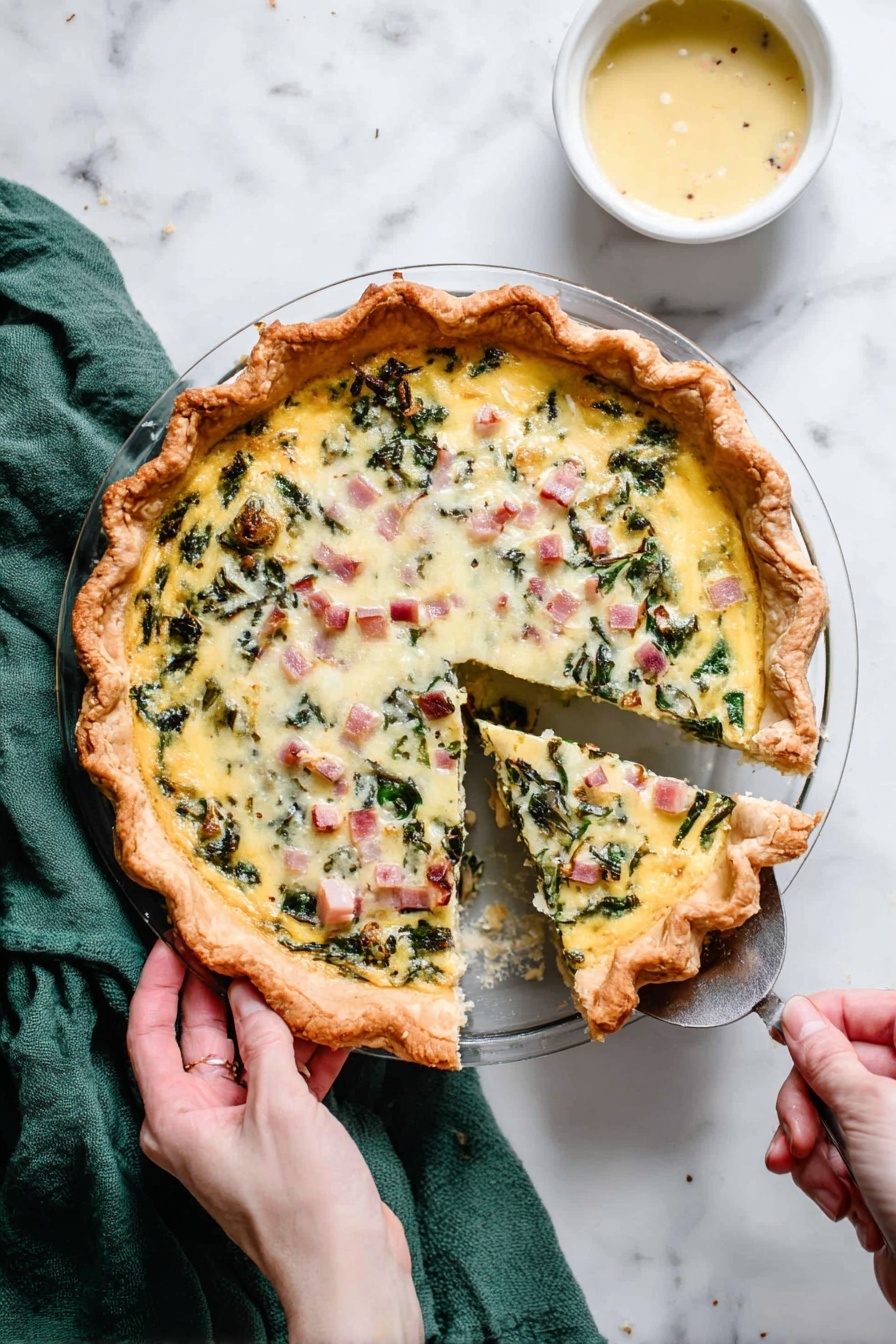 Cheese Quiche, savory brunch dishes, cheesy breakfast recipes, easy quiche recipe, flaky crust quiche - A round pie with a thick golden brown crust holds a creamy egg mixture filled with green leafy vegetables and small cubes of pink ham, topped with melted white cheese and lightly browned spots. One slice is being lifted out with a silver spatula held by a woman's hand on the right, while another woman's hand holds the pie dish handle on the left. The pie sits on a white marbled surface with a green cloth partially visible at the top left and a small white bowl of light yellow sauce at the top right. Photo taken with an iphone --ar 2:3 --v 7