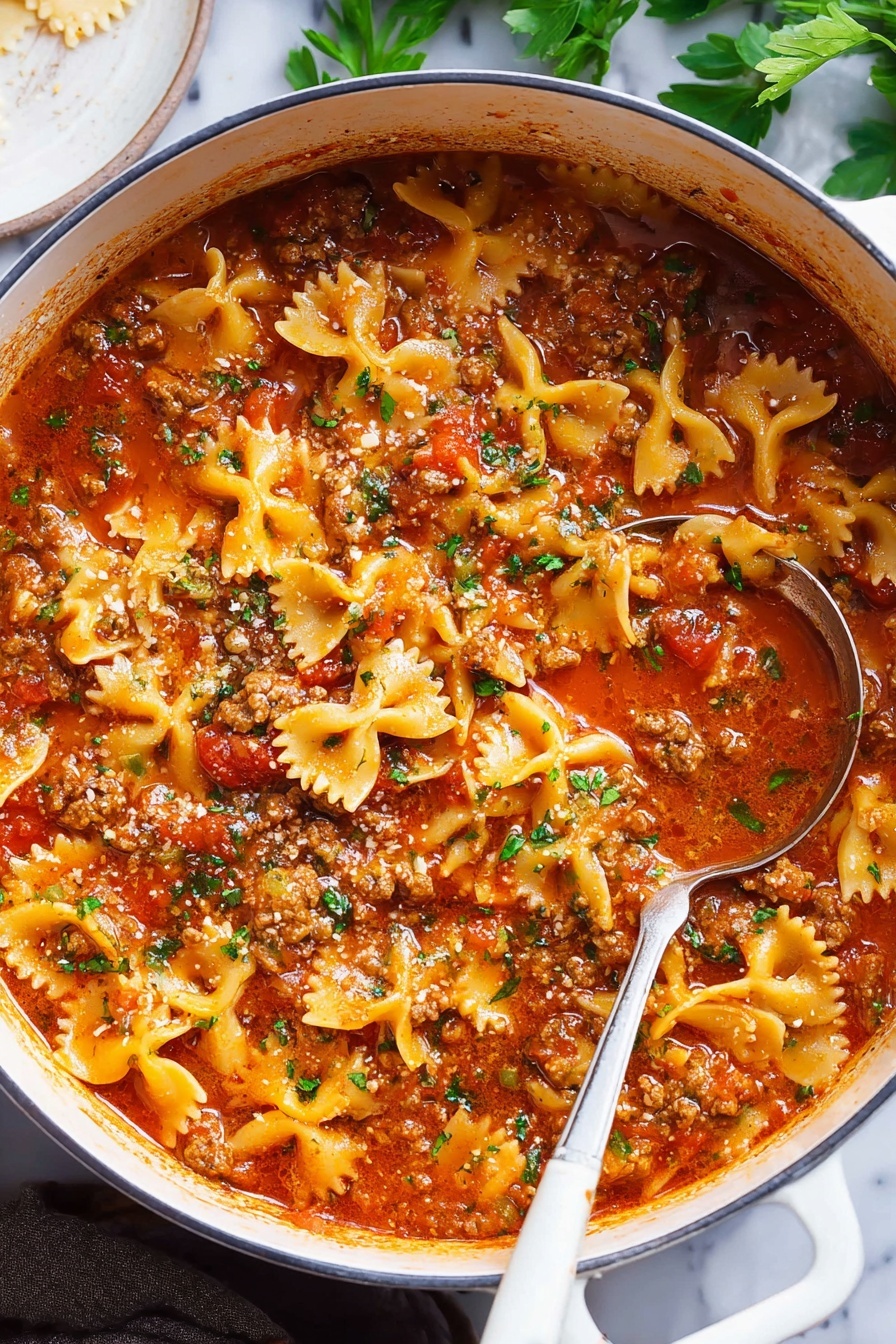 Lasagna Soup with Pasta and Cheese, easy lasagna soup, cheesy soup recipe, hearty tomato soup, weeknight comfort soup - A large white pot filled with a thick stew made of bowtie pasta, ground meat, and rich red tomato sauce, garnished with small bits of green herbs on top; the sauce has a shiny, slightly oily surface with tomatoes and herbs visible throughout. A silver ladle with a white handle rests inside the pot, partially submerged in the stew. The background shows a white marbled surface with some green leaves and a white round dish partially visible on the side. photo taken with an iphone --ar 2:3 --v 7