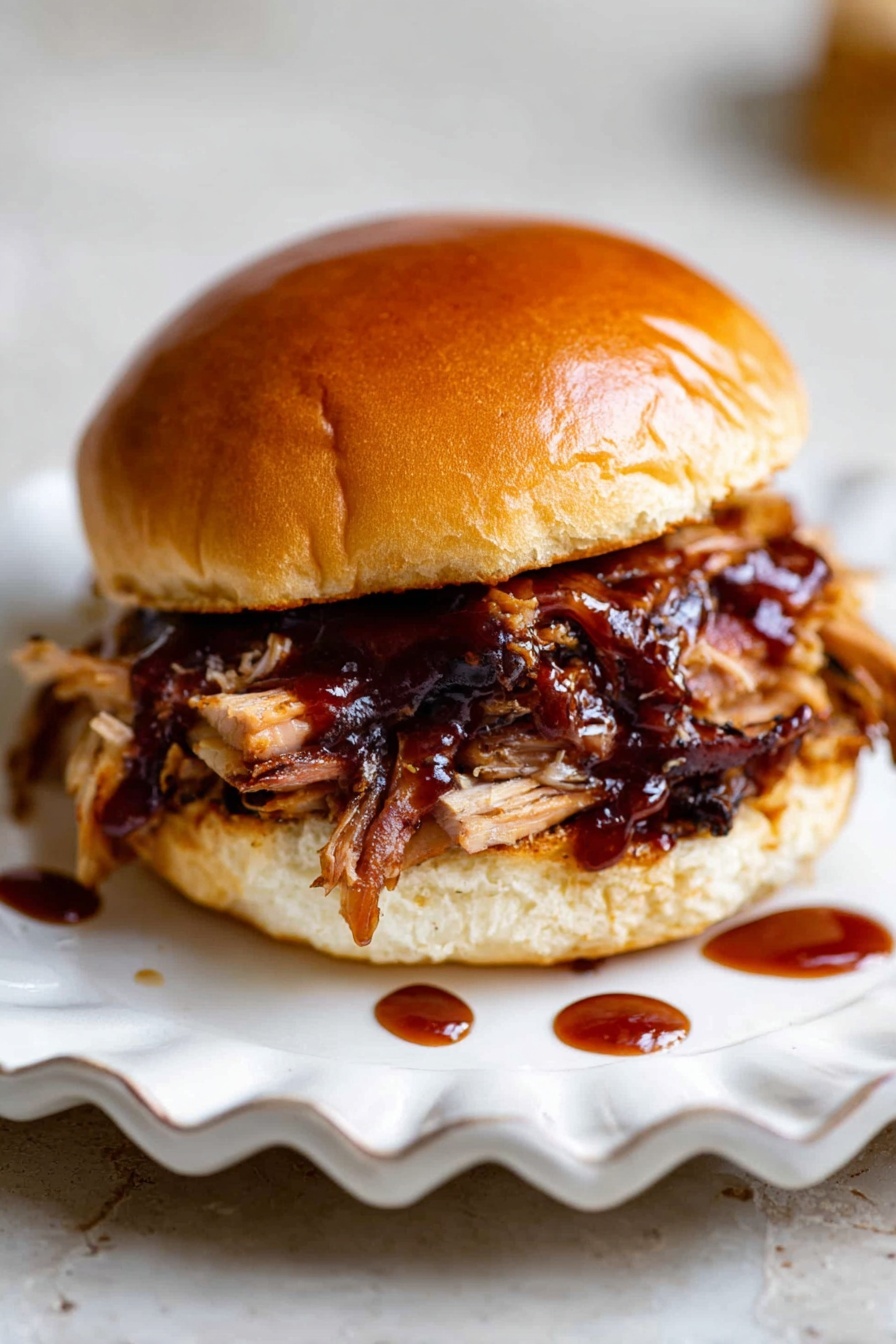 Slow Cooker Pulled Pork, Tender Pulled Pork Recipes, Easy Pulled Pork Dinner, Juicy Slow Cooker Pork, Best Pulled Pork Method - A sandwich with three main layers: the top is a shiny, golden brown bun with a soft texture; the middle layer is pulled meat with charred edges covered in a glossy, dark reddish-brown sauce, adding shine and moisture; the bottom layer is the other half of the bun, also golden brown and soft. The sandwich sits on a white scalloped plate, which rests on a white marbled surface. There are small drops of the dark sauce visible around the plate, adding interest to the scene. photo taken with an iphone --ar 2:3 --v 7