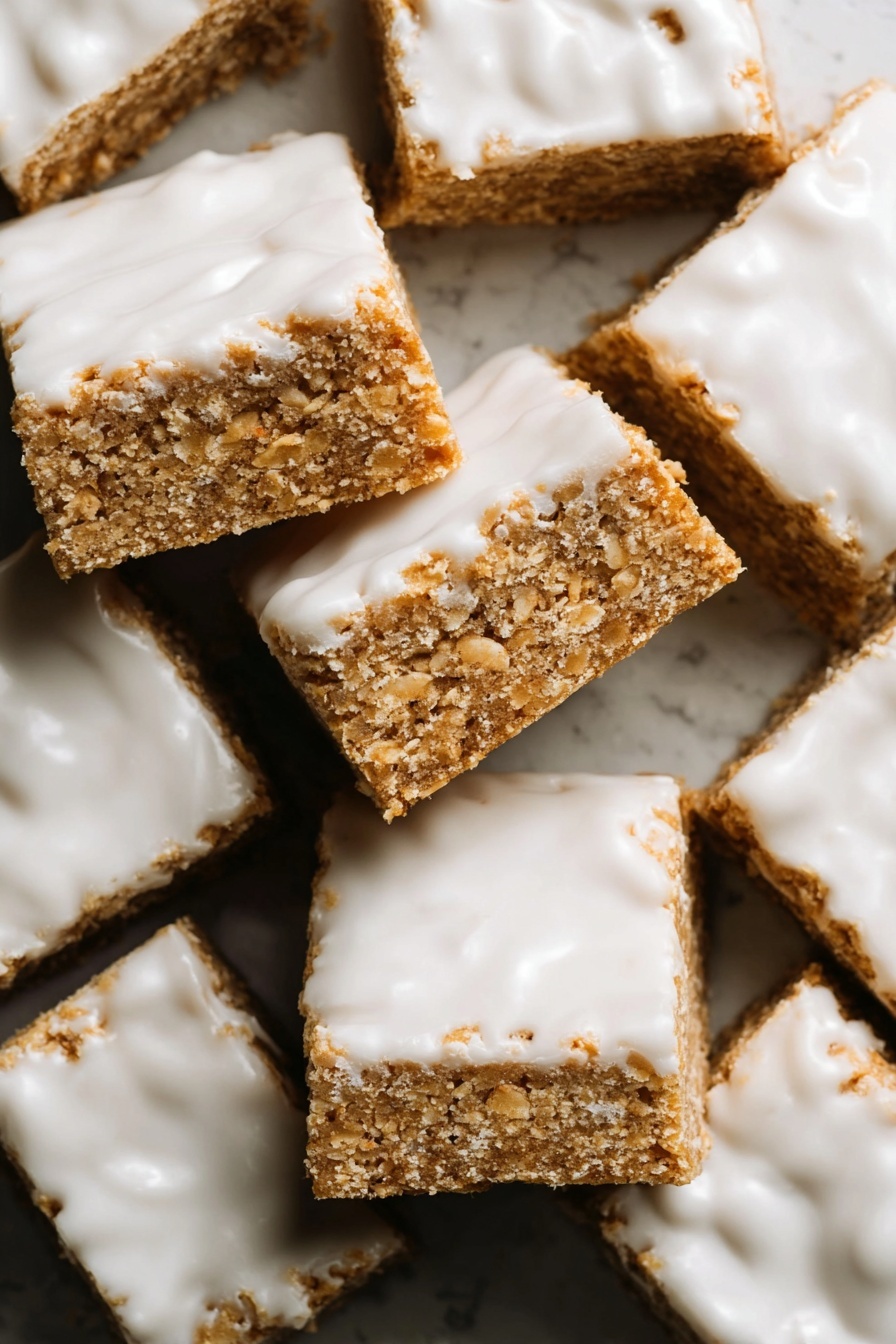 Iced Oatmeal Cookie Bars, oatmeal cookie bars with icing, chewy oatmeal dessert bars, vanilla glazed oatmeal bars, easy oatmeal cookie bar recipe - The image shows many square bars stacked closely together, each bar having two visible layers. The bottom layer is a light brown, crumbly, and textured base that looks like a oat or cookie mixture. The top layer is a shiny white icing that spreads unevenly across the surface, with some areas thicker and others showing the brown base underneath. The bars look soft but firm, with rough edges and a slightly grainy texture. The whole setup is on a white marbled surface. photo taken with an iphone --ar 2:3 --v 7