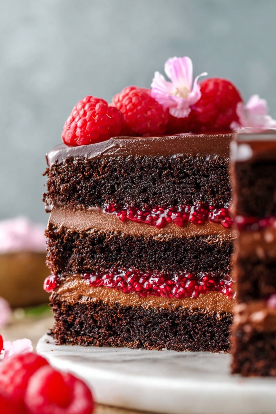Chocolate Raspberry Cake, chocolate raspberry dessert, easy chocolate cake with raspberry filling, moist chocolate cake recipes, festive berry chocolate cake - This image shows a close-up side view of a four-layer chocolate cake on a white marbled surface. The bottom, second, and top layers are dark, moist chocolate cake. Between these, there are three layers: two thick layers of smooth chocolate frosting and one slightly thinner layer of bright red raspberry filling with visible seeds, giving a juicy texture. The whole cake is coated on the outside with glossy chocolate frosting. On top, fresh raspberries and a small delicate pink flower are placed for decoration. The background is blurred with soft neutral tones. photo taken with an iphone --ar 2:3 --v 7